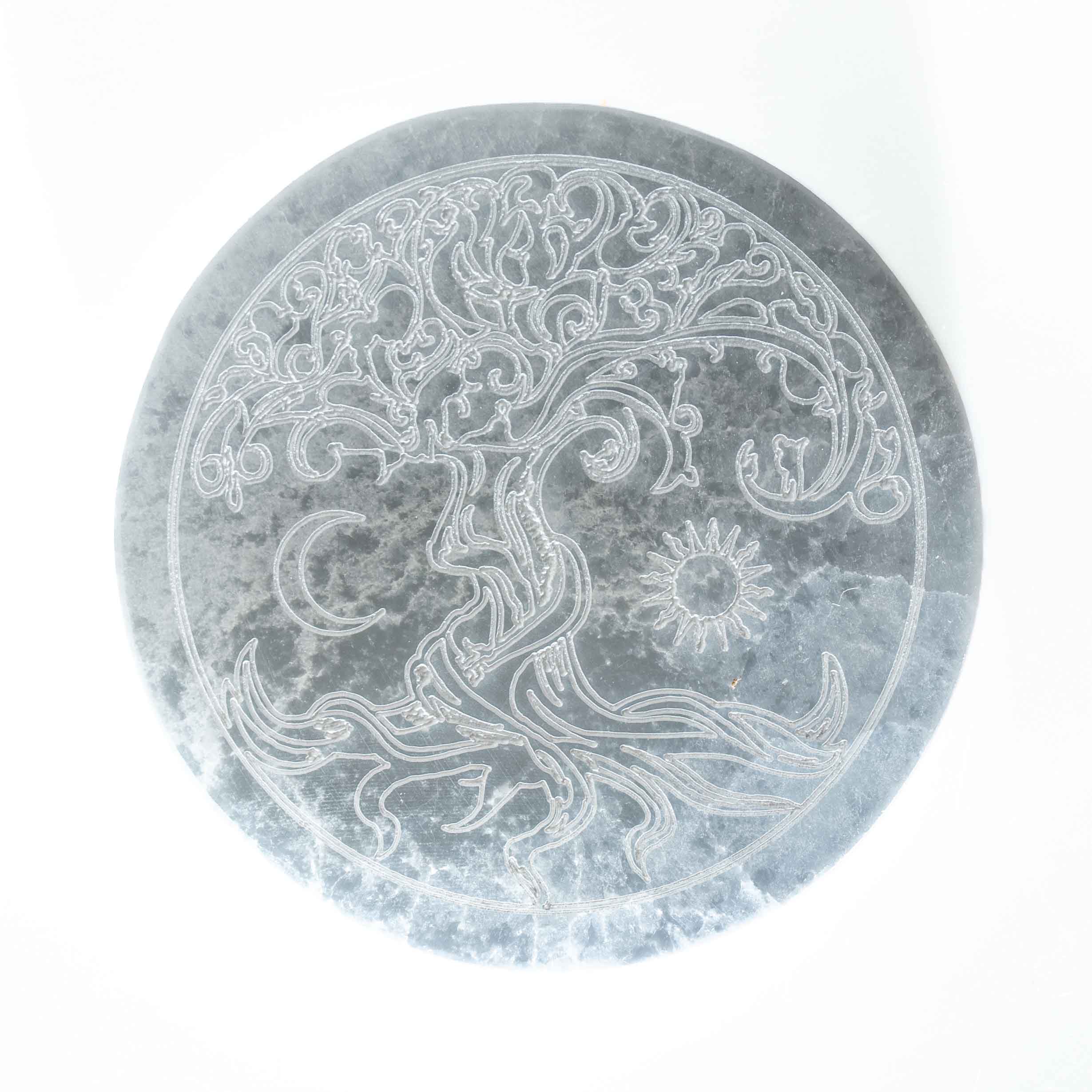 4-inch round gray selenite crystal charging plate engraved with Tree of Life, crescent moon, and sun design on white background.
