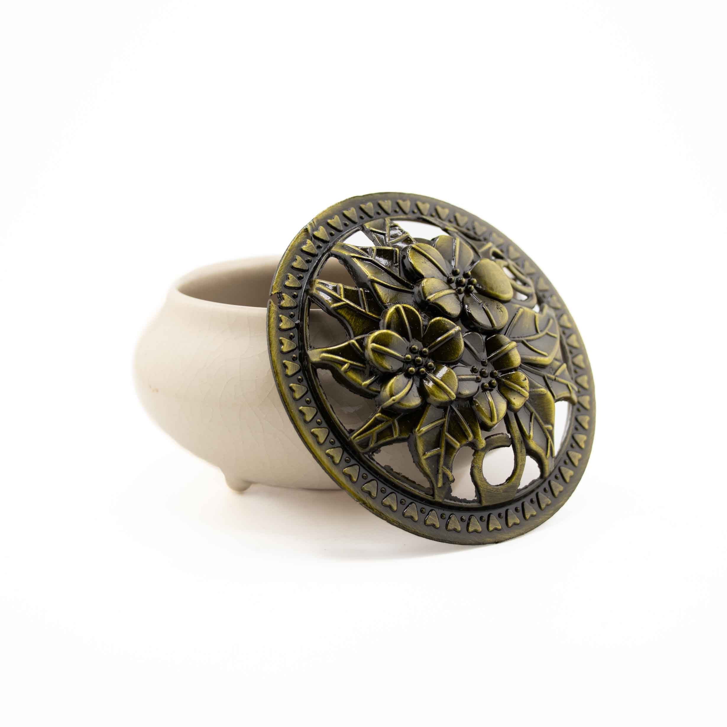 A white ceramic incense burner bowl with an ornate, bronze-finished floral cutout lid.