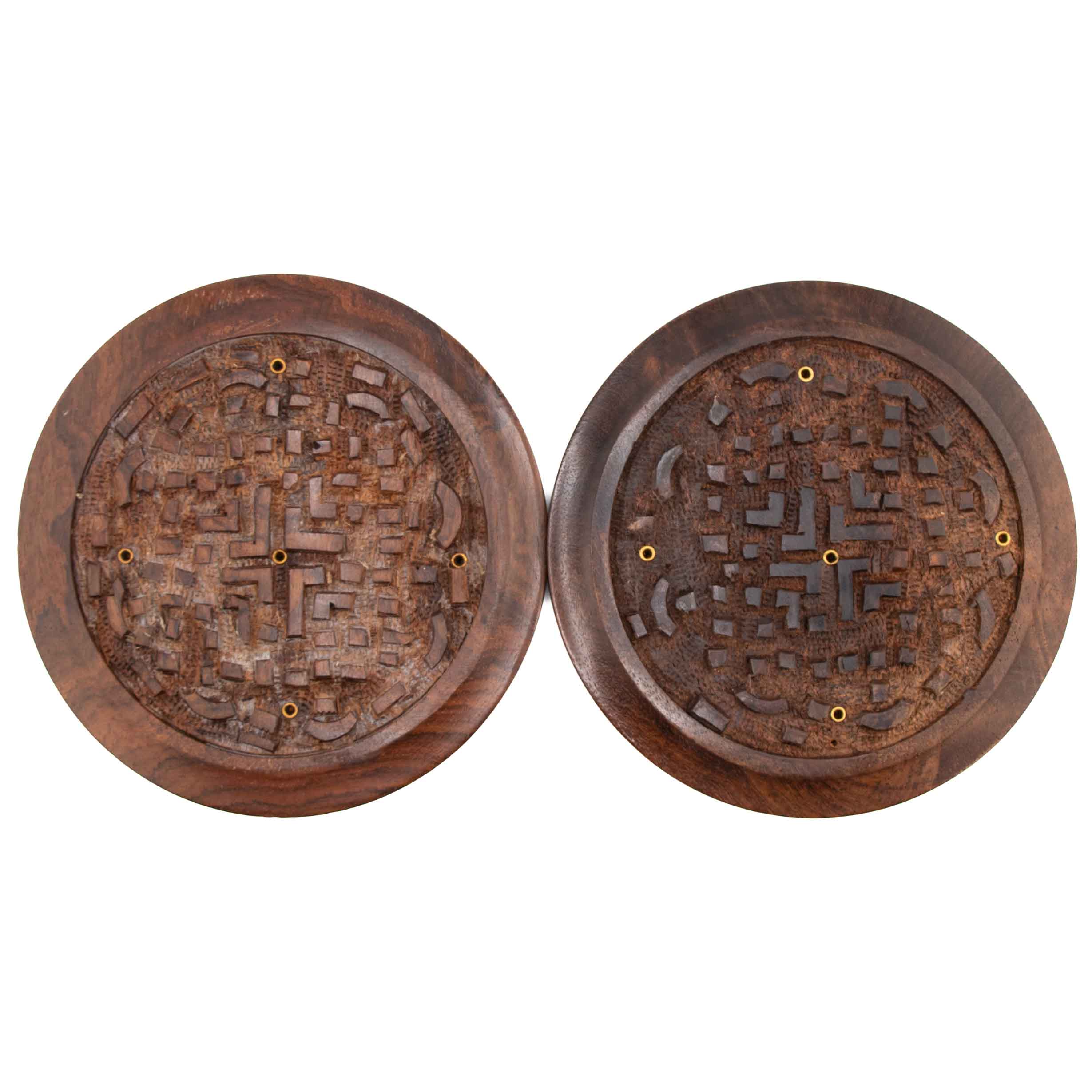 Two circular dark wood incense burners with hand-carved Celtic knot designs and several brass-lined holes for holding incense sticks.