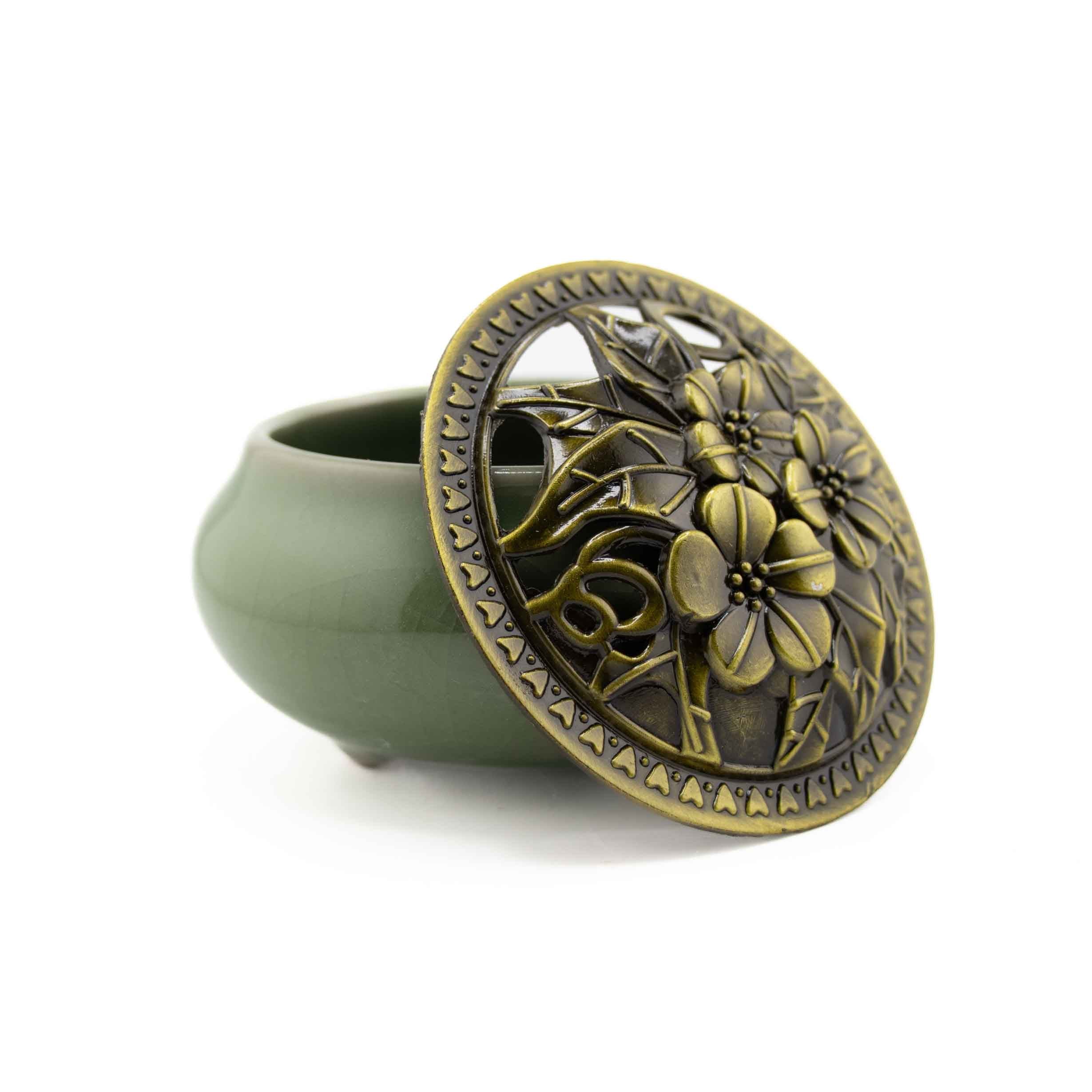 A mint green ceramic incense burner bowl with a matching bronze-finished metal lid featuring an intricate floral cutout design.