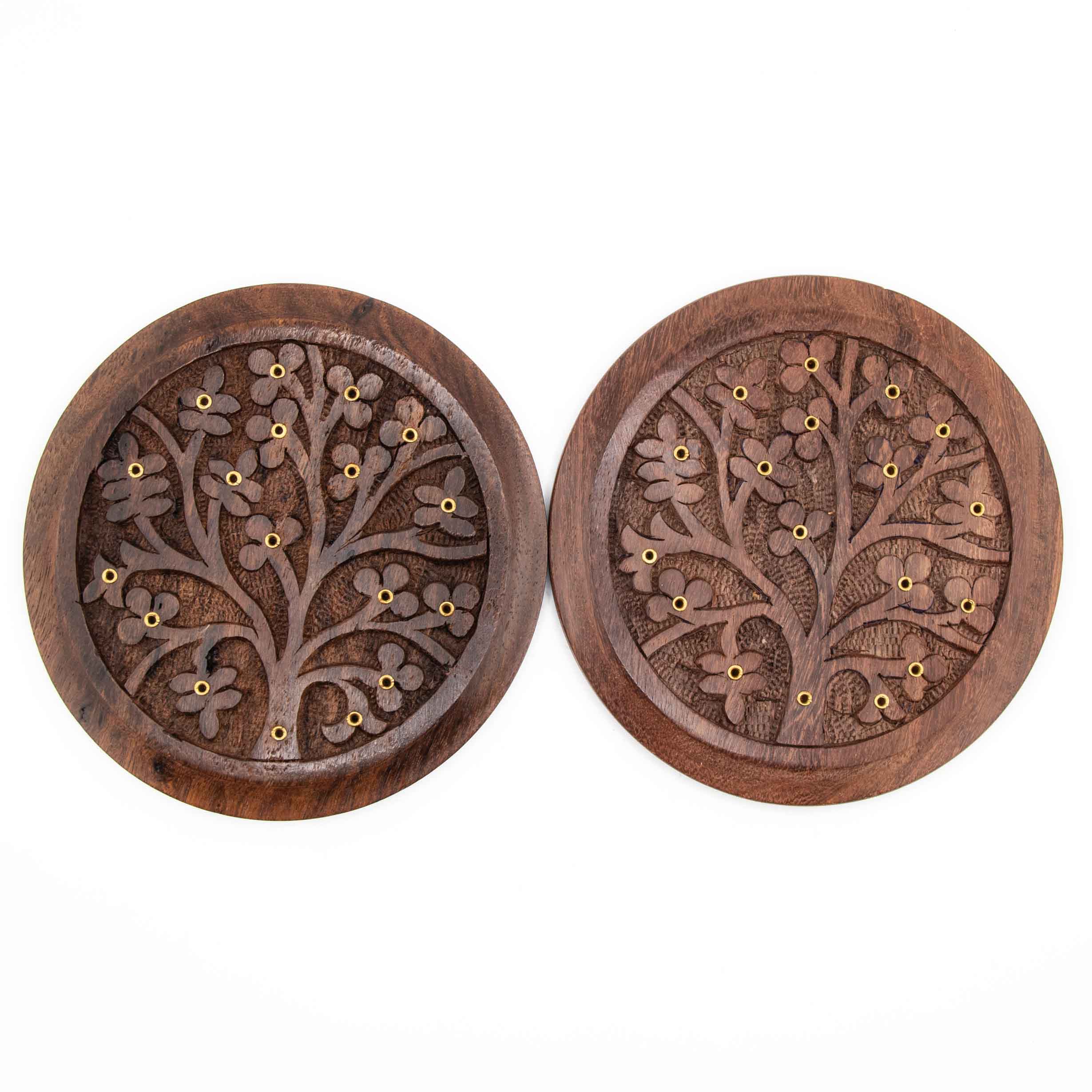 Two circular wooden incense burners featuring an intricately carved Tree of Life design with small brass-lined holes for holding incense sticks.